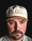 Man wearing a cap with 'BE GOOD' text on a black background