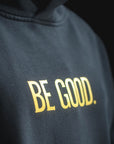Black hoodie with 'BE GOOD.' text in gold on a black background