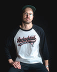 Man wearing a black and white 'Anchorhead' baseball shirt against a black background