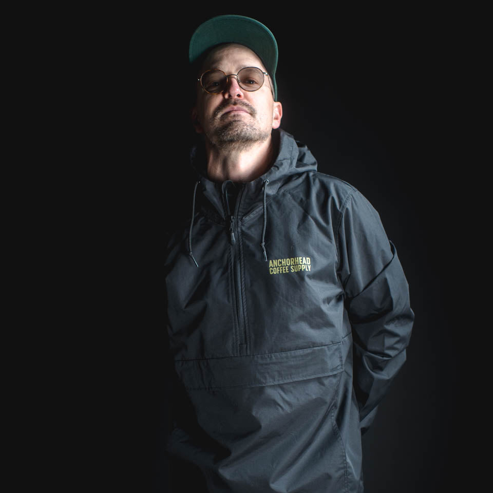 Man wearing a dark jacket with a brand logo on a black background
