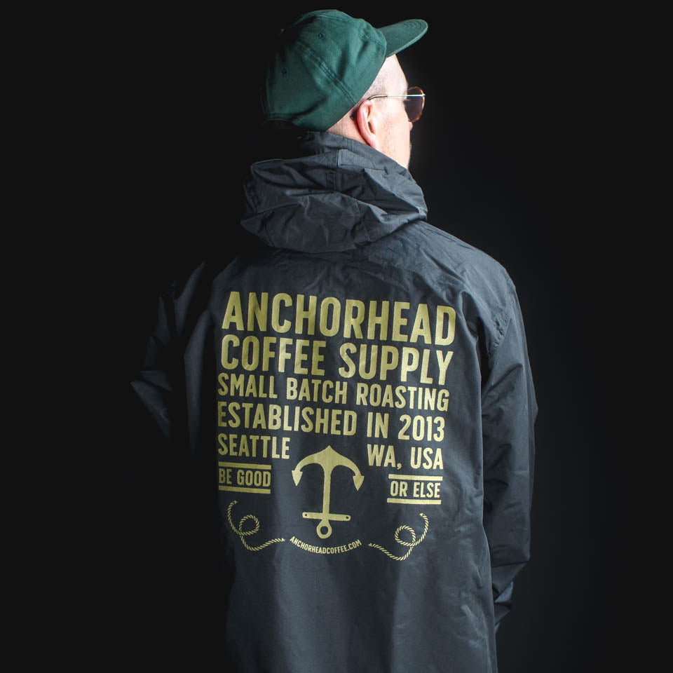 Person wearing a dark jacket with Anchorhead Coffee Supply branding on the back against a black background