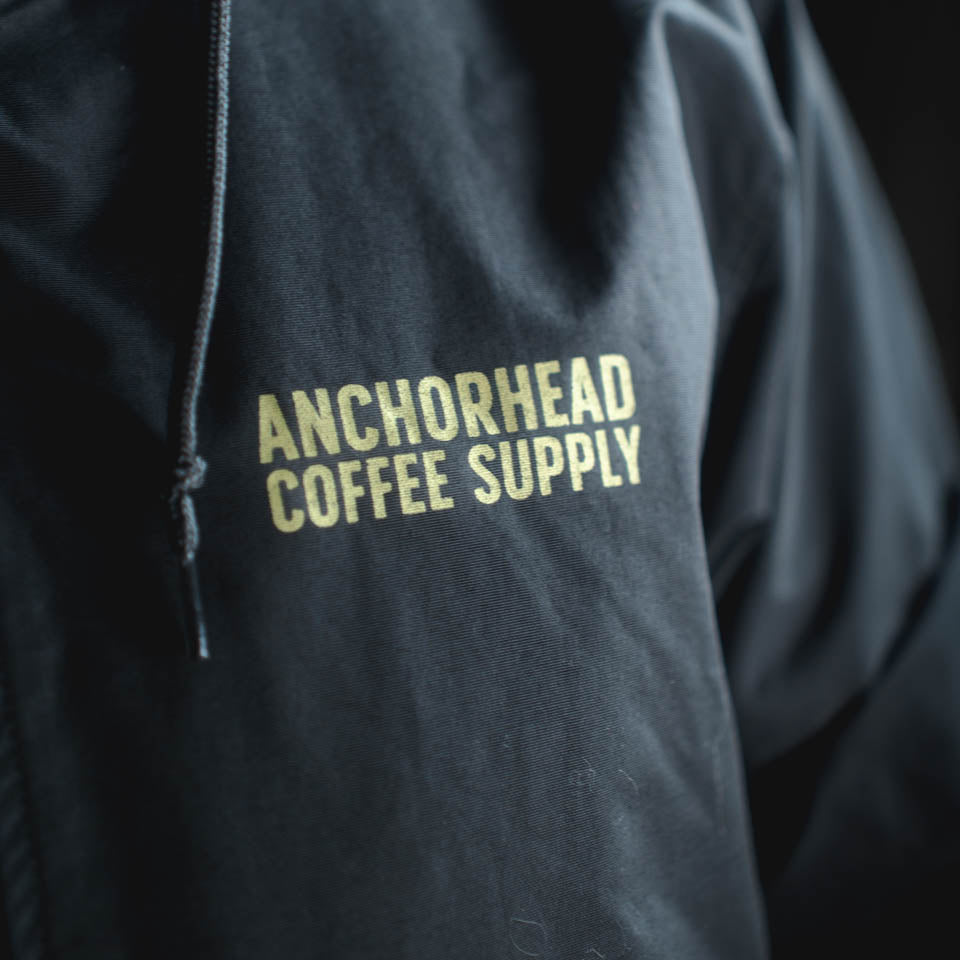 Black jacket with 'Anchorhead Coffee Supply' text in yellow on a dark background