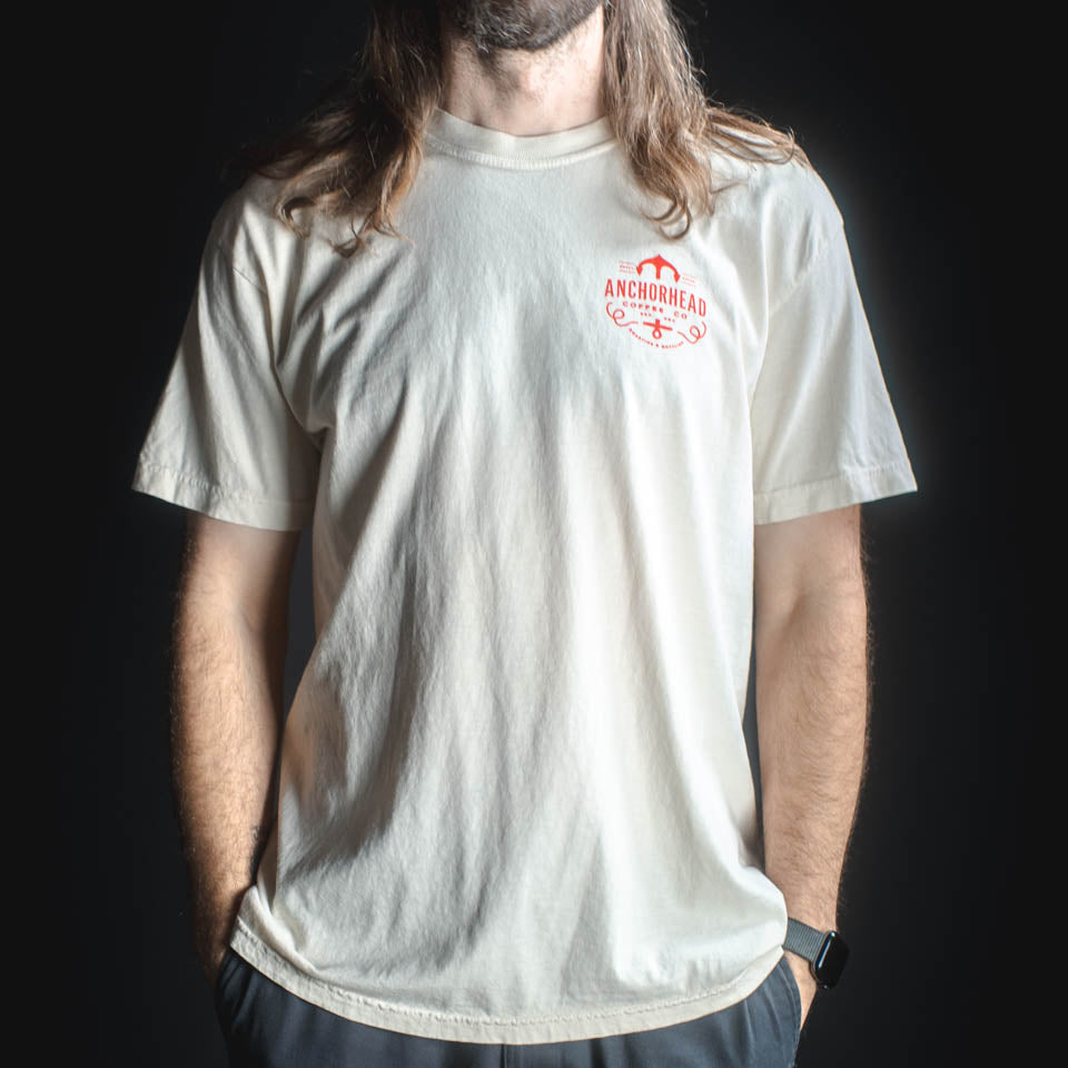 Person wearing a light gray t-shirt with a red logo on a black background
