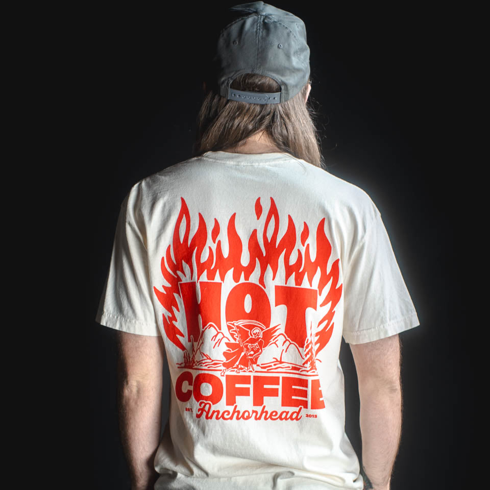 Person wearing a white t-shirt with red graphic and text on the back, standing against a black background.
