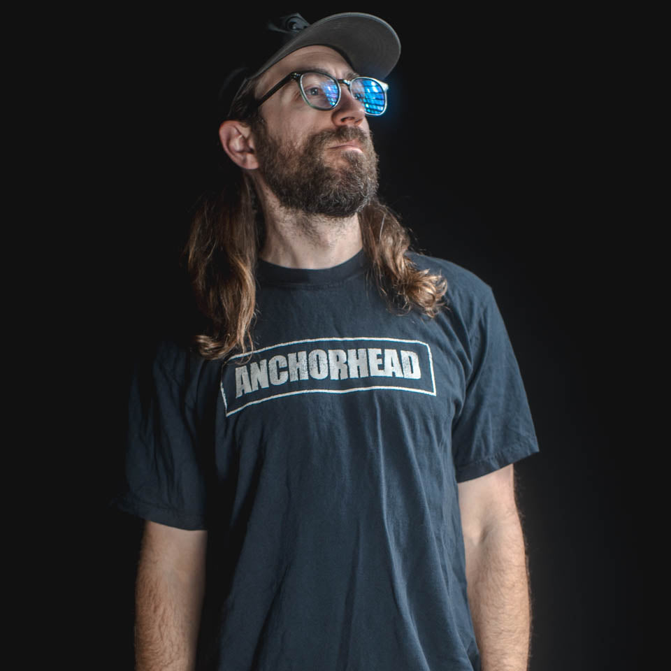 Man wearing a black t-shirt with 'Anchorhead' logo against a dark background