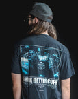 Person wearing a black t-shirt with a graphic design on the back, standing against a dark background.
