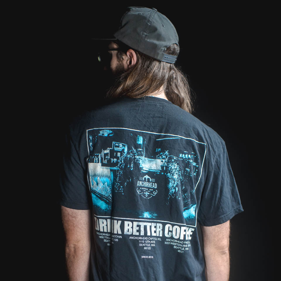 Person wearing a black t-shirt with a graphic design on the back, standing against a dark background.