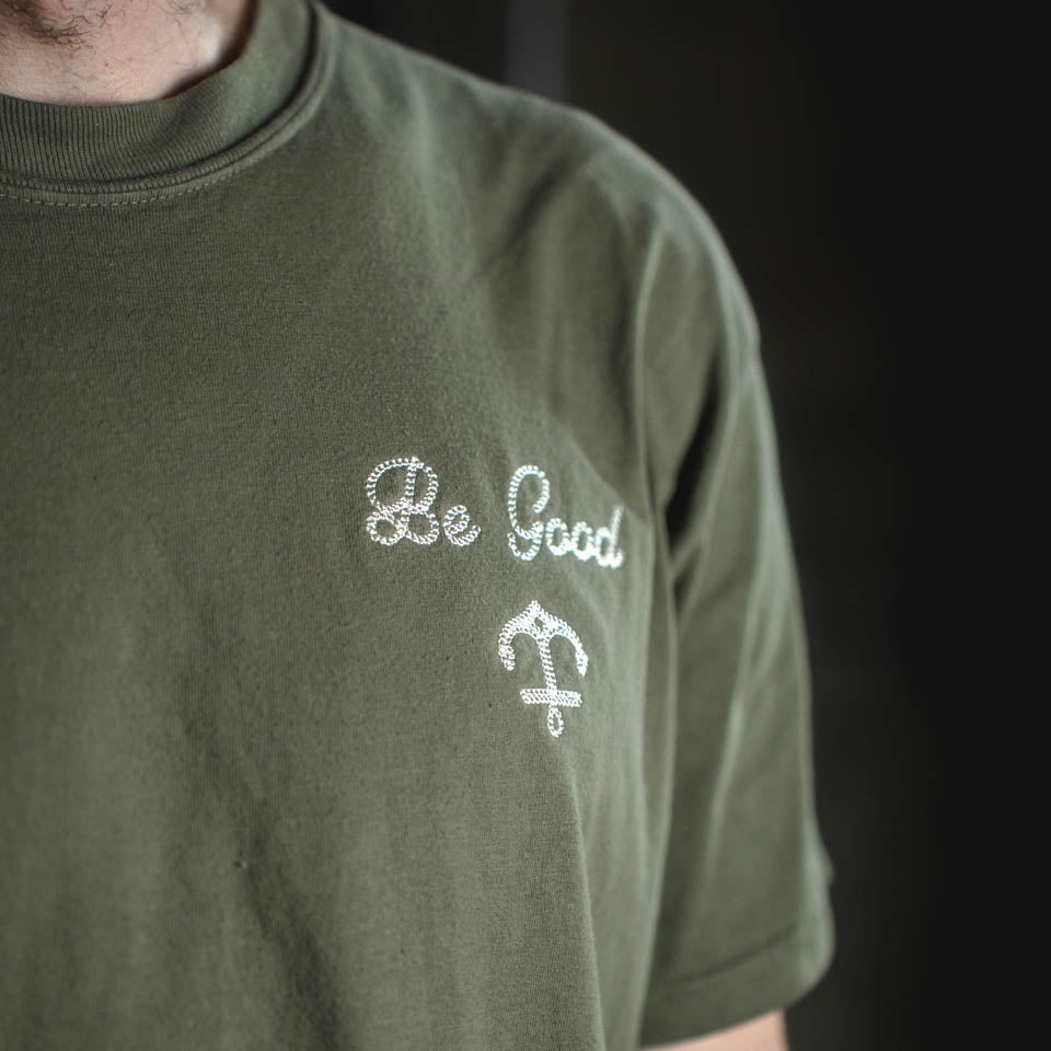 Green t-shirt with 'Be Good' text and symbol on a dark background