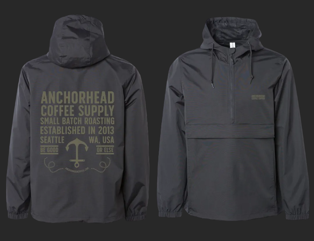 Two views of a black pullover lightweight jacket with hood, featuring text 'Anchorhead Coffee Supply' and anchor graphic in beige on the back.